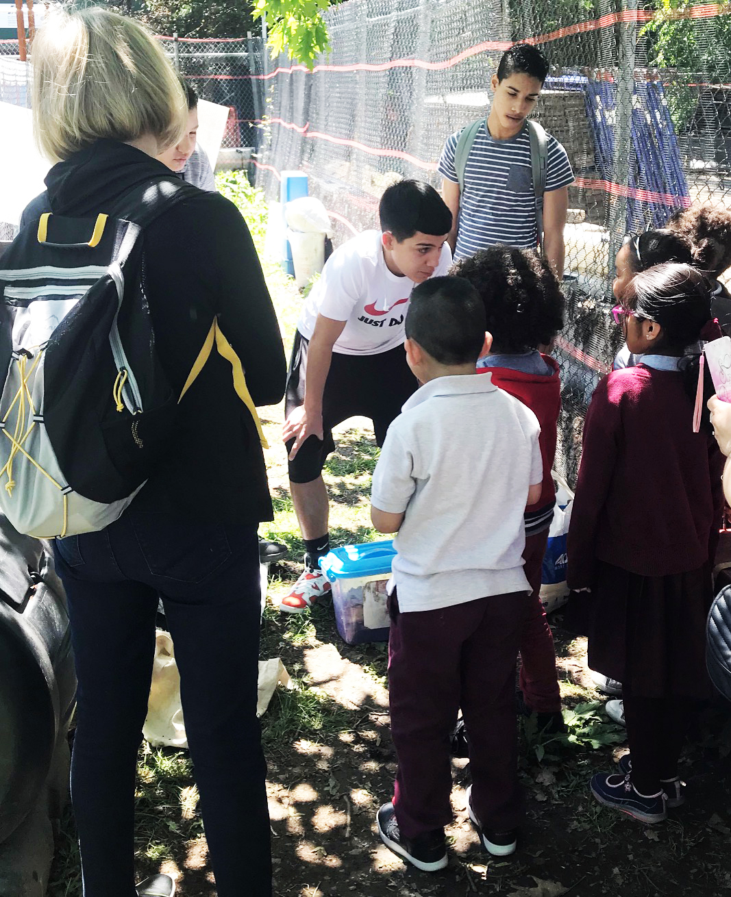 Older kids teaching younger kids; students from ESL class, Bronx Colliation High School teach them about worm bin           composting.
